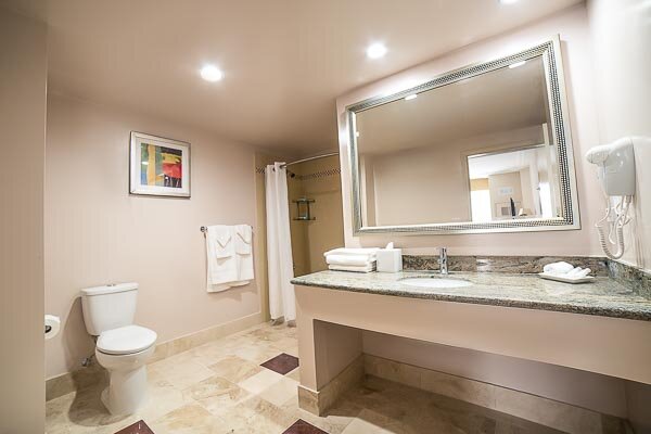 The Double Queen Room bathroom crafted natural stone bathrooms with a shower/tub combo.